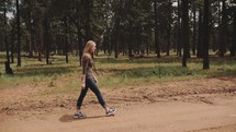 woman walking down a dirt road in slow motion 