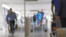 Defocused shot of people with luggage walking through an airport.