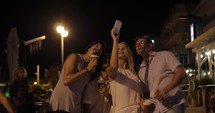 In evening in city of Perea, Greece young company taking selfies on a mobile phone