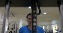 Man at a gym using a pull down weight machine.
