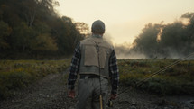 Young fly fisherman walking to a river at dawn