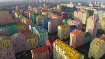 Row of multicoloured terraced houses. A new residential quarter with a colorful facade of high-rise buildings. Top view. Colorful buildings of a residential district. Urban landscape. Cityscape with multicolored houses, cars on the street. Top down view, drone video footage
