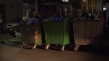 City street with full waste containers, night view