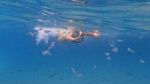 Woman in snorkel mask swimming with fish in the ocean
