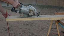 A carpenter sawing a board with a power saw