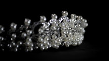 Close-up image of wedding diamond and pearl crown in luxury jewelry shop rotating on black background.