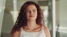 Close up view of hispanic mixed race woman looking to camera. Portrait of serious girl standing home indoors. Concept of people and emotions.
