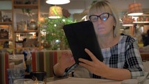 Senior woman surfing internet on pad in cafe