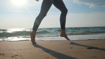 Legs of a young ballet dancer girl on sandy sea shore. 
