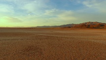 Aerial pullback of a dry lake with cracked earth and distant mountains