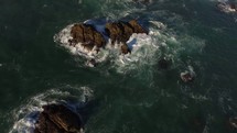 drone flying over rock formations in the ocean 