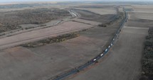 Aerial View Of Large Trucks Driving On The Asphalt Road Between The Rural Fields. 