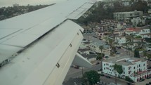 Airplane wing flying over city