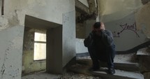 man in an abandoned building with hands over his head 