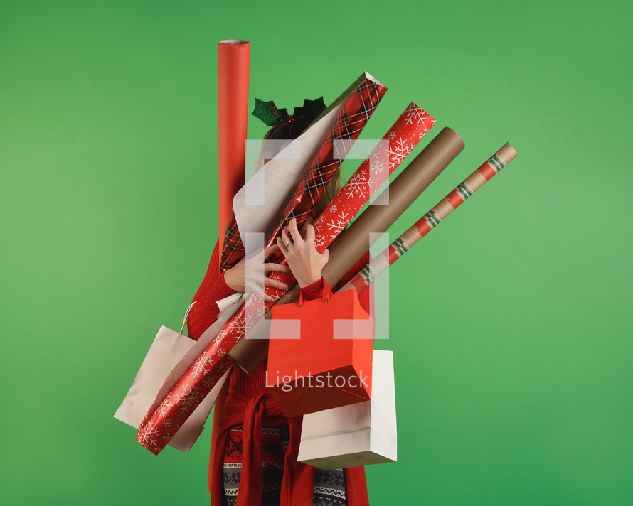a woman holding rolls of Christmas wrapping paper 