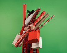 a woman holding rolls of Christmas wrapping paper 