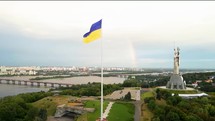 Aerial view of Ukrainian flag and Motherland Monument with rainbow in Kyiv 4k
