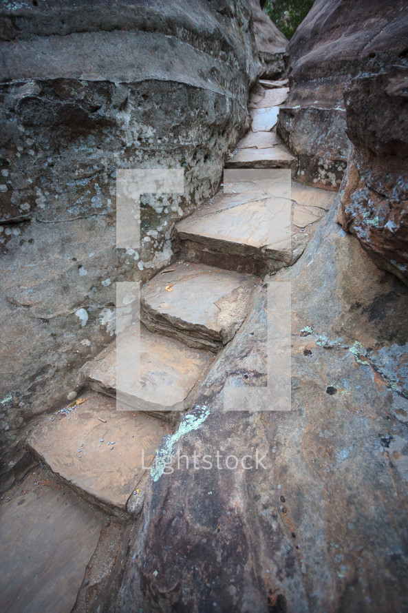 Stone stairs and steps carved between and leading through large grey and brown boulder rocks