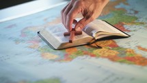 opened Bible and cross on a world map 