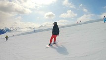 Woman Snowboarding Fast on Ski Slope Mountain. Snowboarder having fun snowboarding backcountry on a sunny winter day in snowy mountains.