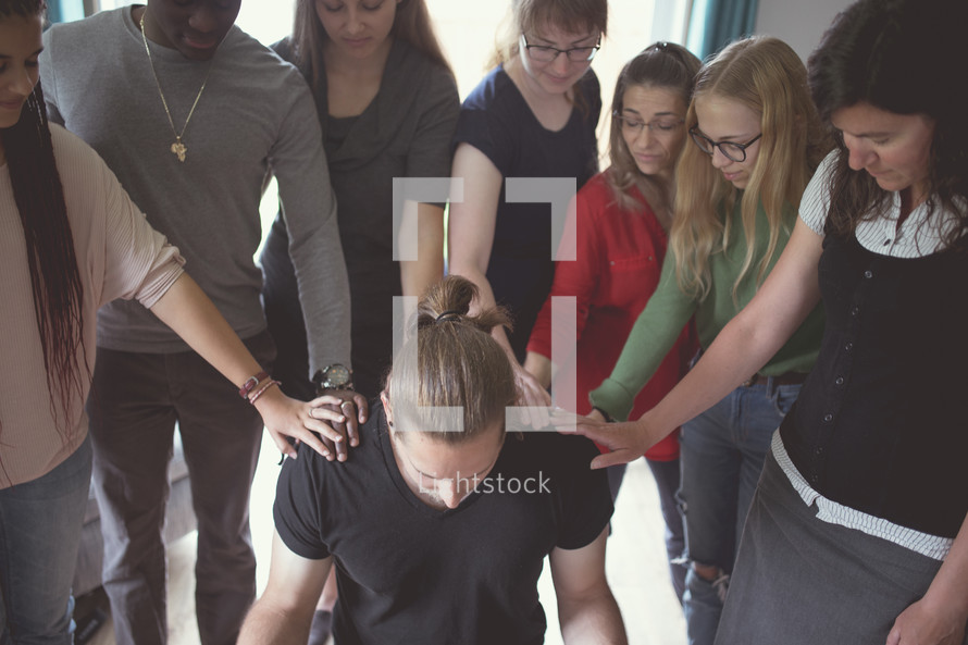 group laying hands on a man praying over him 