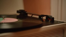 A hand placing the needle on a record player that begins to spin