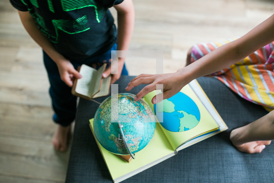 a boy reading a Bible and a girl playing with a globe 
