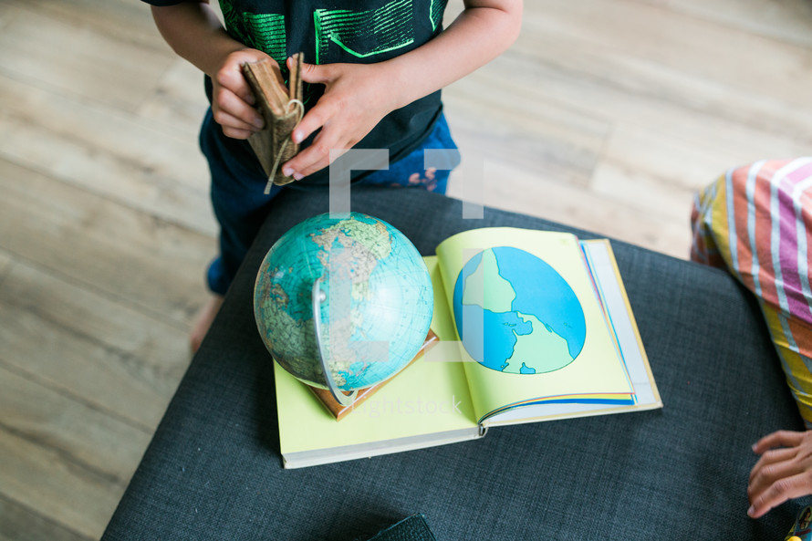 children reading a Bible and playing with a globe 