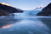Frozen lake reflecting Mendenall Glacier and mountains.