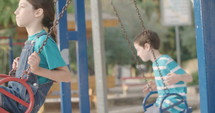 Children swinging together at a public playground.