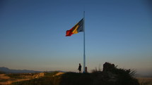 The Romanian flag flies proudly on top of mountain.