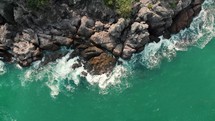 aerial view over waves washing into rocks 