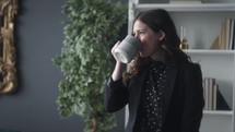 a woman drinking coffee in a home office 
