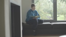 Young woman reading her Bible by window.