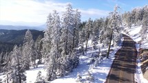 drone over a road and snow on a mountainside 