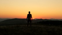 silhouette of a man standing on a mountaintop at sunset 