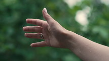 Female hand catching rain drops on green summer tropical background. Enjoying monsoon, environment recovery, freshness, purity, life-giving force. High quality 4k footage