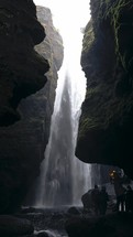 People Visiting A Cave Under A Waterfall In Iceland 