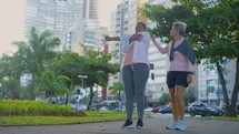 Elderly female friends, stretching in preparation for morning routine workout or exercise together outside. Senior female friends having a warm up stretch for cardio training or exercising
