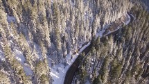 aerial view above forest with snow and road 