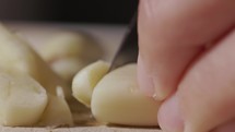 Chef's Hand Cutting Fresh Peeled Garlic With A Knife. - close up shot