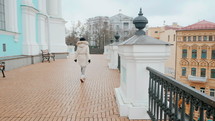 Woman in warm coat walking down old stone stairs in the street. Slow motion. Lifestyle concept. Young girl in European city, winter or autumn time.