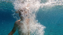 Underwater view of boy jumping into the water at a pool