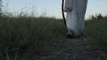 A man in Biblical times walking in a field with his staff. 