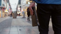 a man carrying a Bible down a city sidewalk 