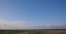 Onshore Horizontal Axis Wind Farm Turbine In Green Field At Clear Blue Sky - wide angle shot