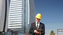 engineer in a hardhat standing in front of a skyscraper 