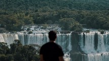 Man Looking At The Scenic Iguazu Falls Of Brazil And Argentina - Medium Shot