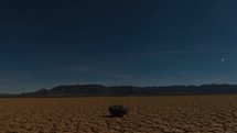 Tracking timelapse of the stars and moonlight over a dry lake in the desert