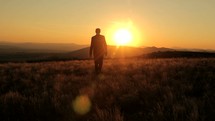 a businessman walking away at sunset 